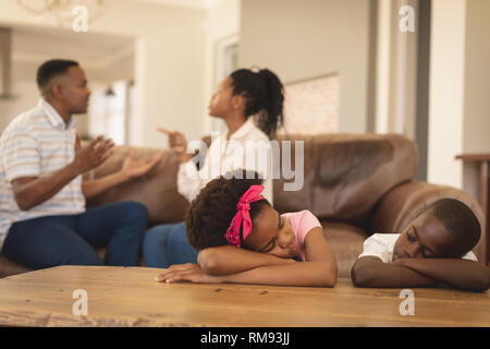African American children leaning on table while parents arguing on the sofa Stock Photo