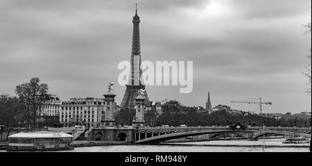 Moody cityscape panorama with Pont Alexandre III bridge, Seine river and Eiffel Tower in Paris, France in black and white treatment Stock Photo