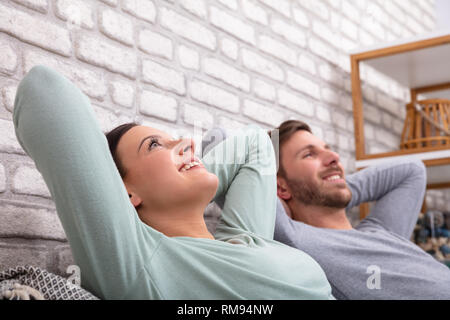Happy Young Couple Relaxing On Sofa At Home Stock Photo