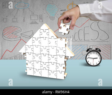 Assembling puzzles for house shape on desk in office Stock Photo
