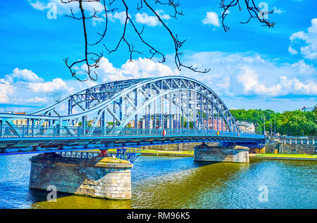 The modern metal construction of Marshal Jozef Pilsudski bridge across the Vistula river with riding trams and cars, Krakow, Poland. Stock Photo