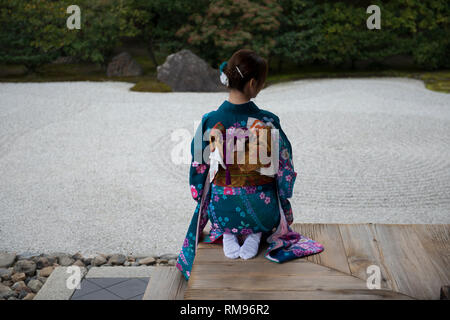 Geisha on Pavilion Verandah, Woman dressed in traditional kimonos outside pavillion kneeling by Japanese rock garden, Karesansui in Japanese, Kenni