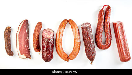 Line of assorted spicy seasoned sausages and a portion of cured ham, bacon or kassler isolated on a panorama banner format white background Stock Photo
