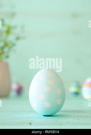Easter egg standing on its blunt end, decorated in blue stars. Close-up view with blurred cyan background with copy space Stock Photo