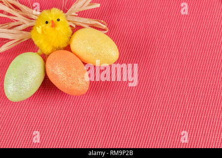 A cheerful easter chicken with three colored eggs on a pink background and space for text. Stock Photo