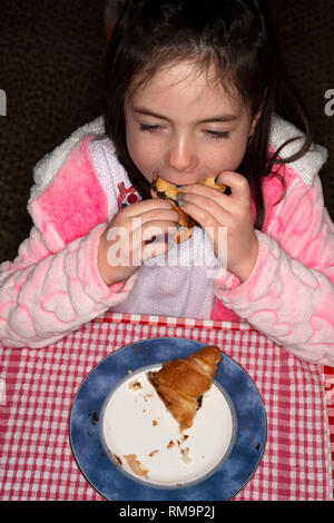 Young girl eating chocolate filled croissant for breakfast Stock Photo