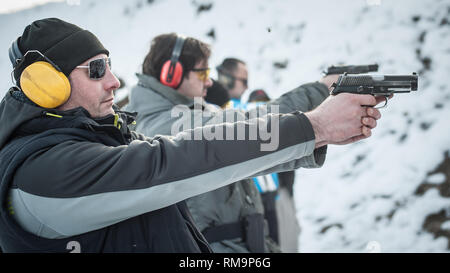 Group of civilian practice gun shoot on target on outdoor shooting range. Civilian team weapons training Stock Photo