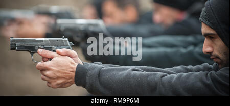 Group of civilian practice gun shoot on target on outdoor shooting range. Civilian team weapons training Stock Photo