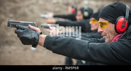 Group of civilian practice gun shoot on target on outdoor shooting range. Civilian team weapons training Stock Photo