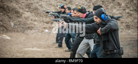 Group of civilian practice gun shoot on target on outdoor shooting range. Civilian team weapons training Stock Photo