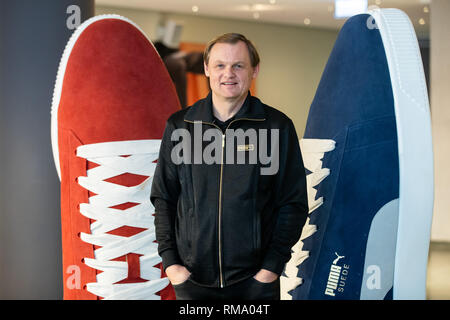 14 February 2019, Bavaria, Herzogenaurach: Björn Gulden, chairman and managing director of the sporting goods manufacturer Puma SE, stands on the sidelines of the company's balance sheet pk next to two oversized shoes. Photo: Daniel Karmann/dpa Stock Photo