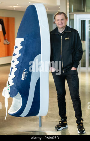 14 February 2019, Bavaria, Herzogenaurach: Björn Gulden, chairman and managing director of the sporting goods manufacturer Puma SE, stands on the edge of the company's balance sheet next to an oversized shoe. Photo: Daniel Karmann/dpa Stock Photo