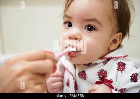 Portrait of baby brushing teeth with help of mom Stock Photo