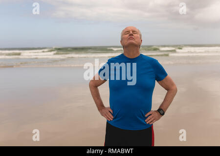 Senior man standing with hands on hip at the beach Stock Photo