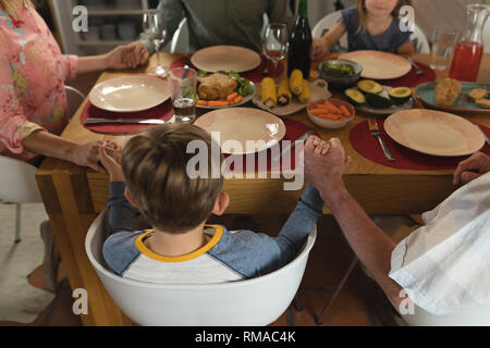 Family praying together before having meal on dining table Stock Photo