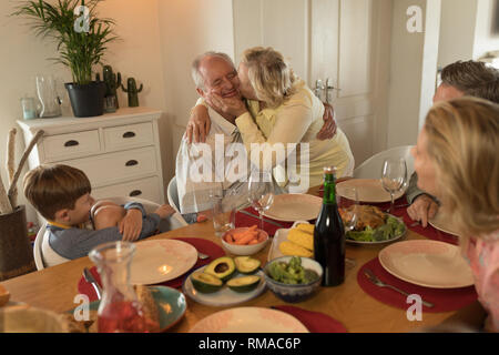 Family interacting with each other while having meal on dining table Stock Photo