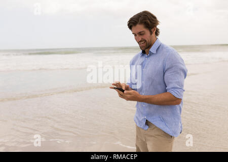 Man using mobile phone on the beach Stock Photo