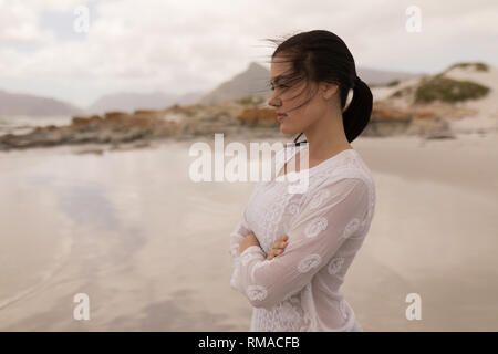 Woman standing with arms crossed on the beach Stock Photo