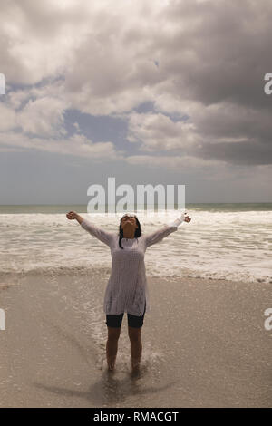 Young woman with arms stretched out standing on beach Stock Photo