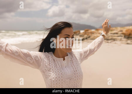 Happy young woman with arms stretched out standing on beach Stock Photo