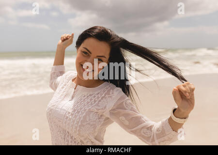 Young woman with arms stretched out standing on beach Stock Photo