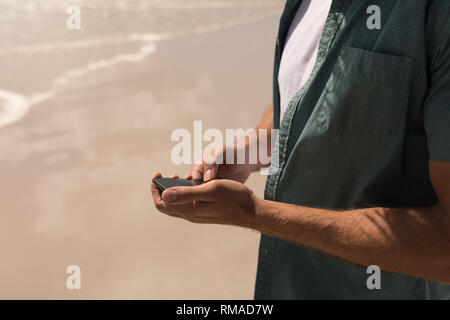 Young man using mobile phone on beach Stock Photo