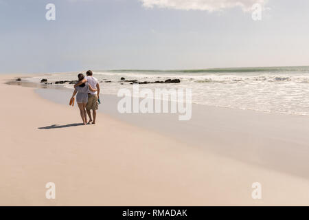 Romantic young couple walking with beach footwear on beach Stock Photo