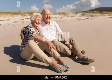 Happy senior couple sitting on beach Stock Photo