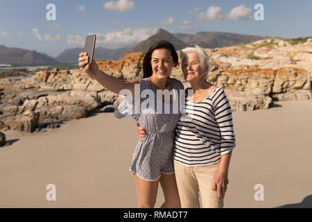 Happy young woman taking selfie with her mother on beach Stock Photo