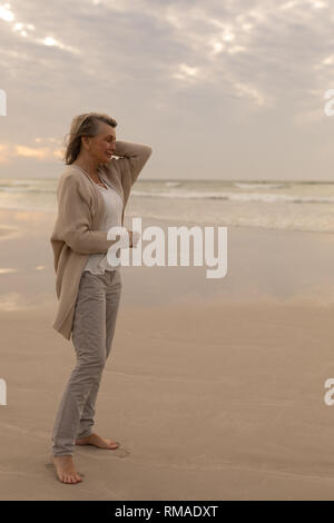 Senior woman standing with eyes closed on the beach Stock Photo