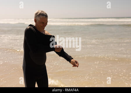Side view of senior male surfer wearing wet suit on the beach Stock Photo