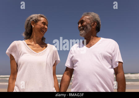 Senior couple holding hands and looking each other on beach Stock Photo