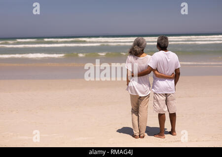 Senior couple standing on a beach with their arms around each other Stock Photo