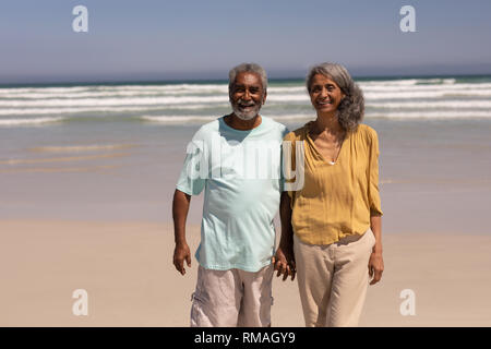 Senior couple holding hands and standing on beach Stock Photo