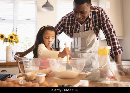 African American father and daughter baking cookies in kitchen Stock Photo
