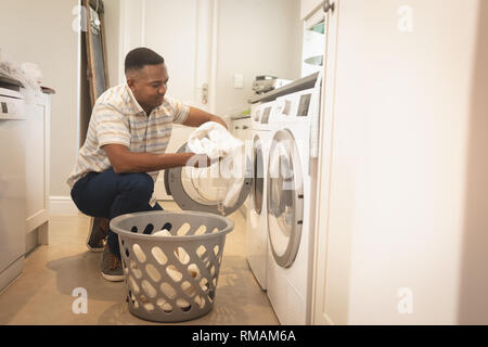 African American man washing clothes in washing machine Stock Photo