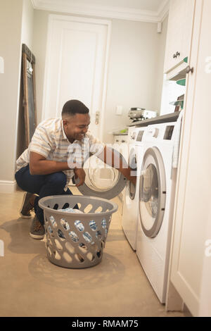 African American man washing clothes in washing machine Stock Photo