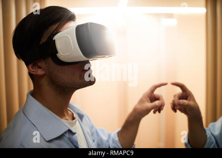 Casual guy with vr headset touching mirror display while working or traveling in virtual reality Stock Photo