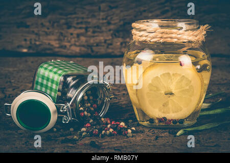 Olive oil flavored with lemon and peppercorns on wooden table, shabby style photo. Stock Photo