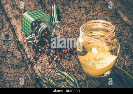 Olive oil flavored with lemon and peppercorns on wooden table, shabby style photo. Stock Photo