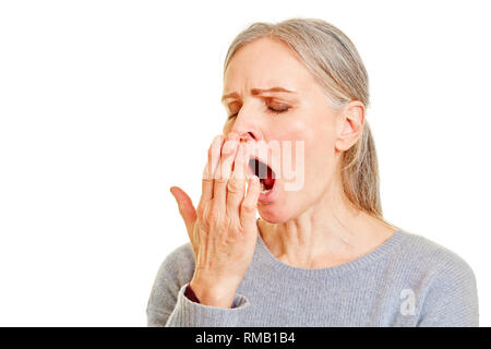 Tired older woman yawning holding her hand over her mouth Stock Photo
