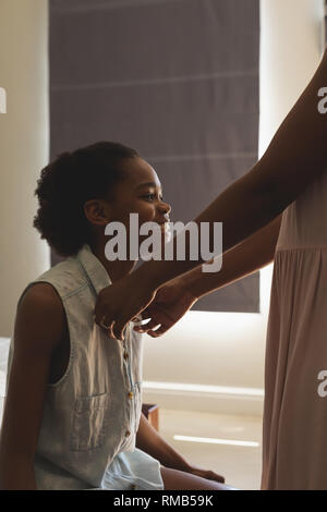 African American mother helping her daughter to wear a cloth in bedroom