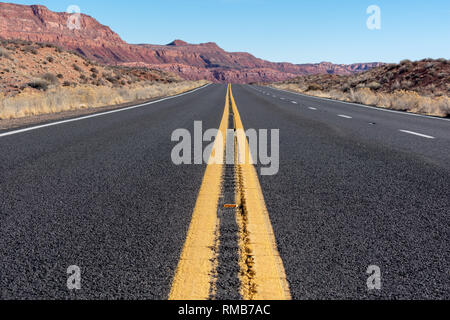 Close up. Empty rural two lane highway in desert with passing climbing lane and raised reflective markers with mountains in distance