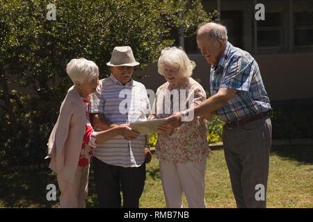 Front view of senior friends discussing over digital tablet in garden Stock Photo