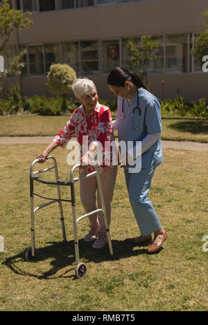 Young female doctor helping disabled senior woman in garden Stock Photo