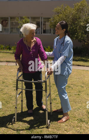 Young female doctor helping disabled senior woman in garden Stock Photo