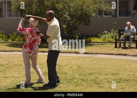 senior couple dancing together in garden Stock Photo