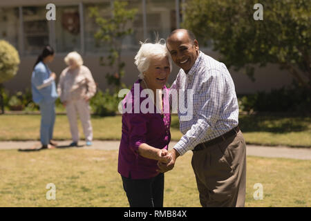 senior couple dancing together in garden Stock Photo