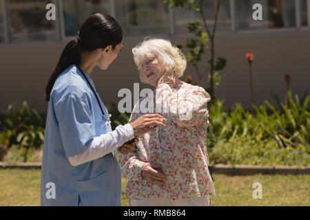 young female doctor examining senior woman in garden Stock Photo