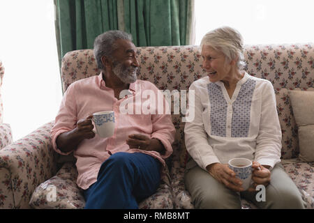 Senior couple interacting with each other while having coffee in living room Stock Photo